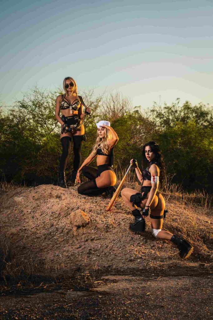 A dramatic sunset desert scene featuring three women in themed costumes posing with power and confidence. Inspired by HiFi Scottsdale’s ‘World War Fi’ Halloween theme, this image captures fearless fashion and the spirit of Scottsdale nightlife.